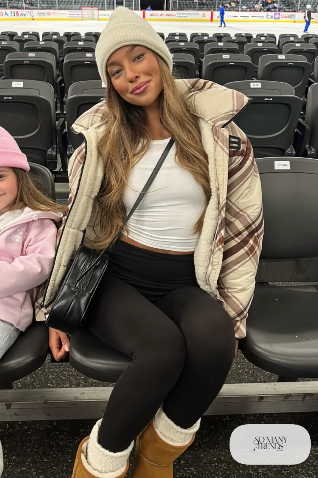 Woman in brown plaid quilted shacket, white thermal tee, black fleece-lined leggings and tan suede boots, hockey game outfit 9