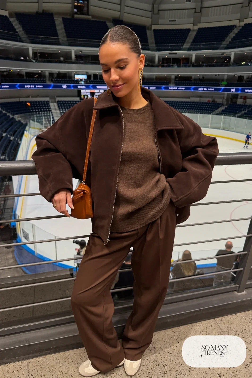 Woman in brown suede-look jacket, cocoa knit sweater, chocolate wide-leg pants and cream sneakers, hockey game outfit 15