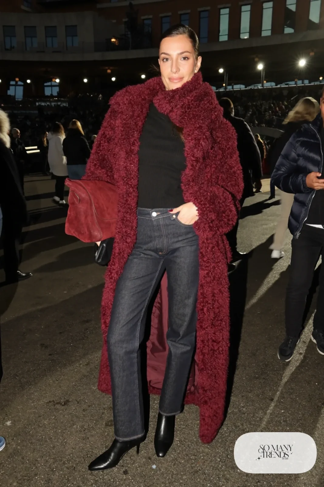 Woman in a burgundy teddy coat with matching scarf, black knit, dark jeans and black boots, basketball game outfit 10