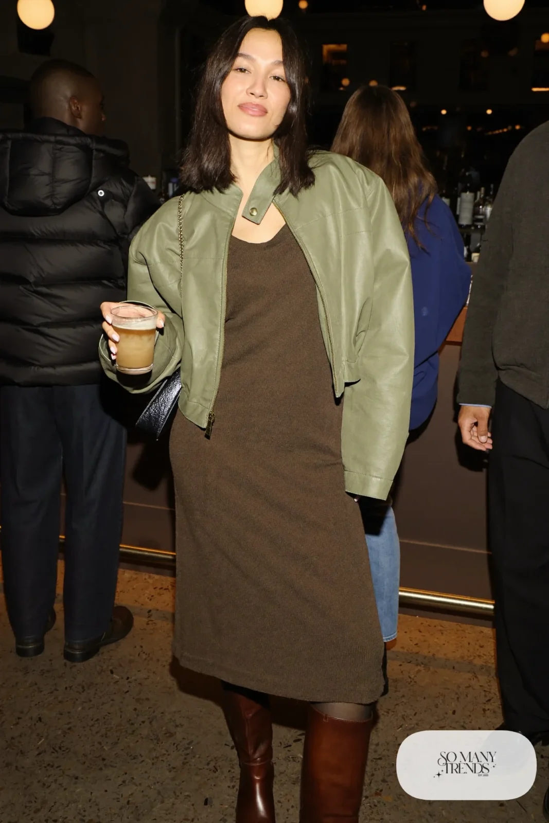Woman in an espresso ribbed knit midi dress, cropped sage jacket and tall brown boots, basketball game outfit 12
