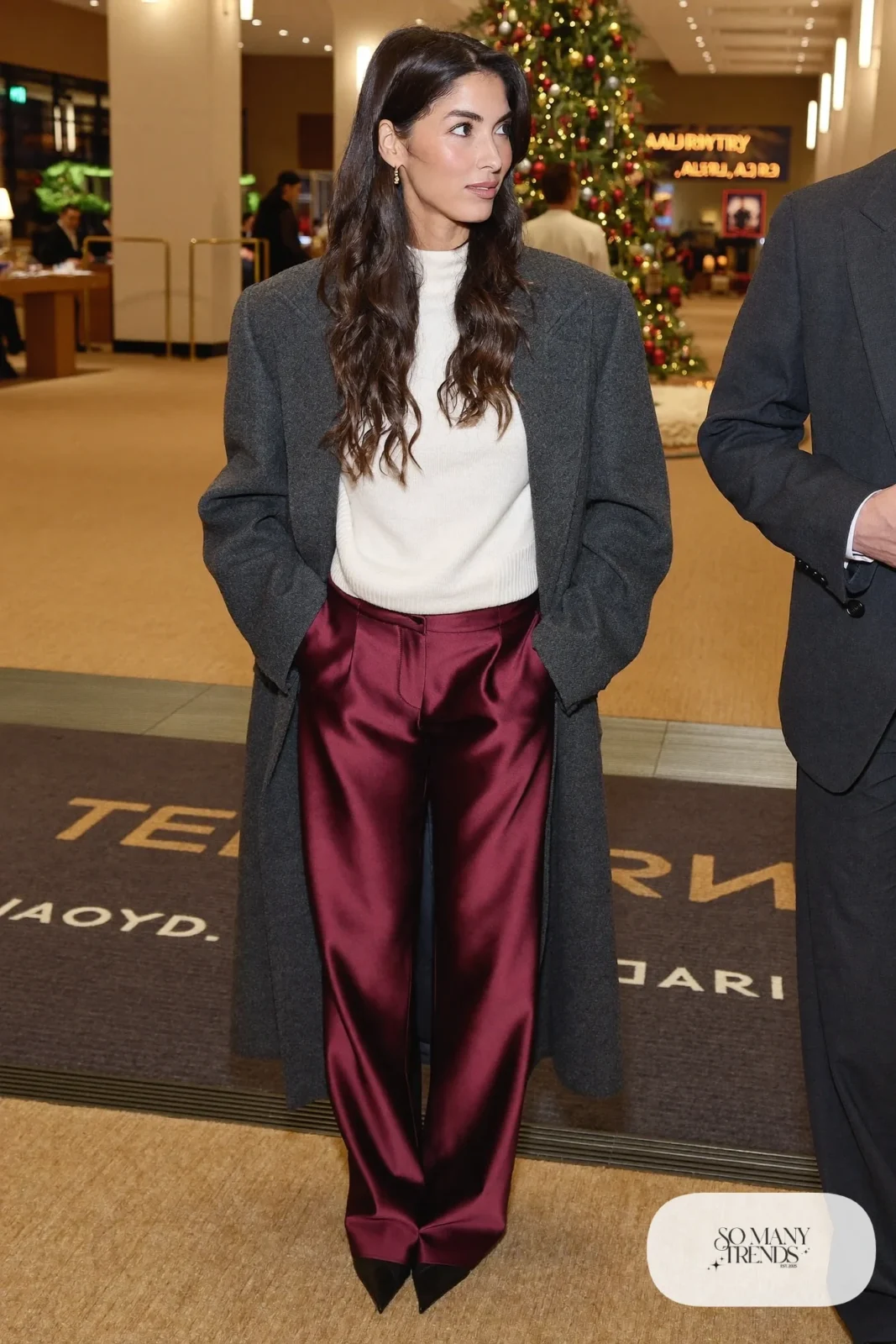 burgundy satin wide-leg pants, cream fine-knit sweater tucked in, black pointed pumps, gold hoops, charcoal coat, nutcracker outfit 20