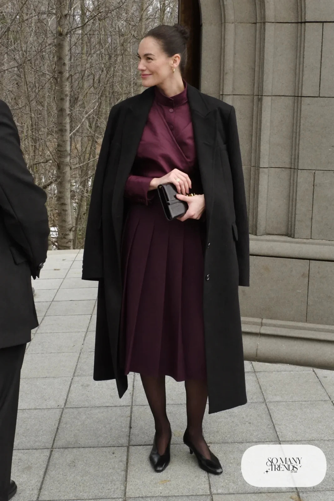 dusty plum satin wrap blouse, wine pleated midi skirt, black slingback pumps, sheer tights, long black wool coat, winter wedding guest outfit 9