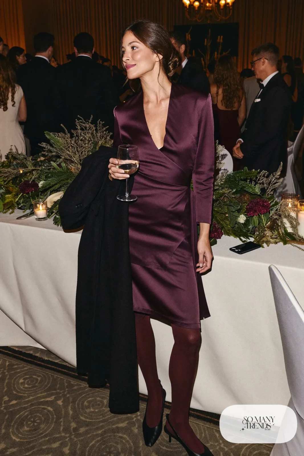plum satin long-sleeve top and matching midi skirt set, long black coat, black slingback pumps, sheer tights, winter wedding guest outfit 17