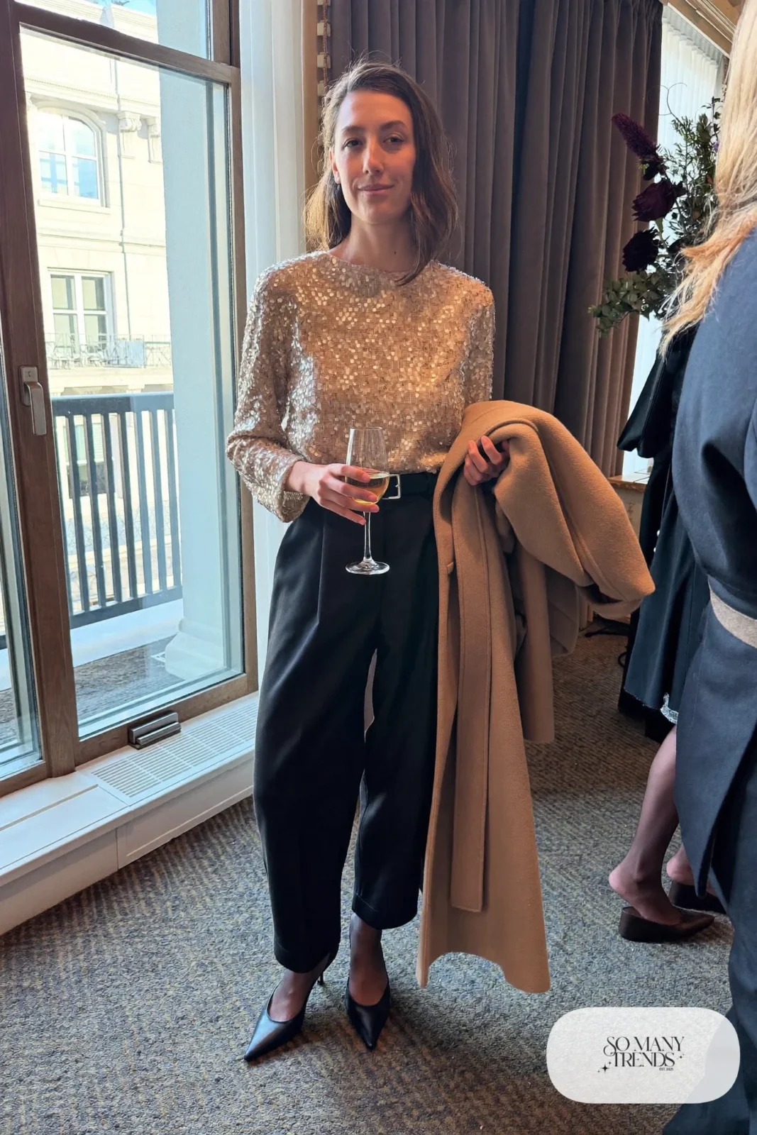 black wide-leg high-waisted crepe pants, champagne sequin long-sleeve top, black pointed pumps, long belted wool coat, winter wedding guest outfit 20