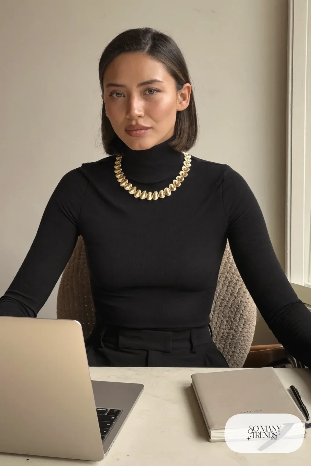 black fine knit turtleneck with gold petal collar necklace seated at a desk, interview outfit 25