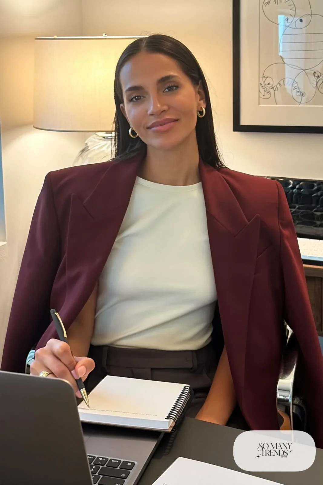 burgundy structured blazer over ivory tee with small hoops seated at a desk, interview outfit 27