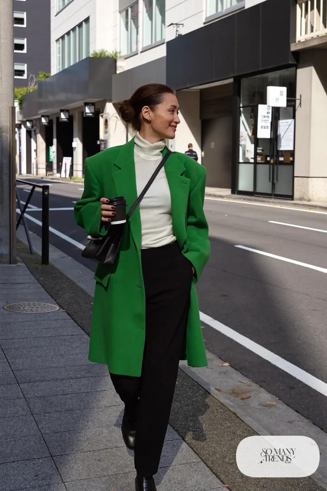 Woman in a long emerald wool coat over a pearl turtleneck, black straight pants and black leather loafers on a Tokyo street, outfit 1