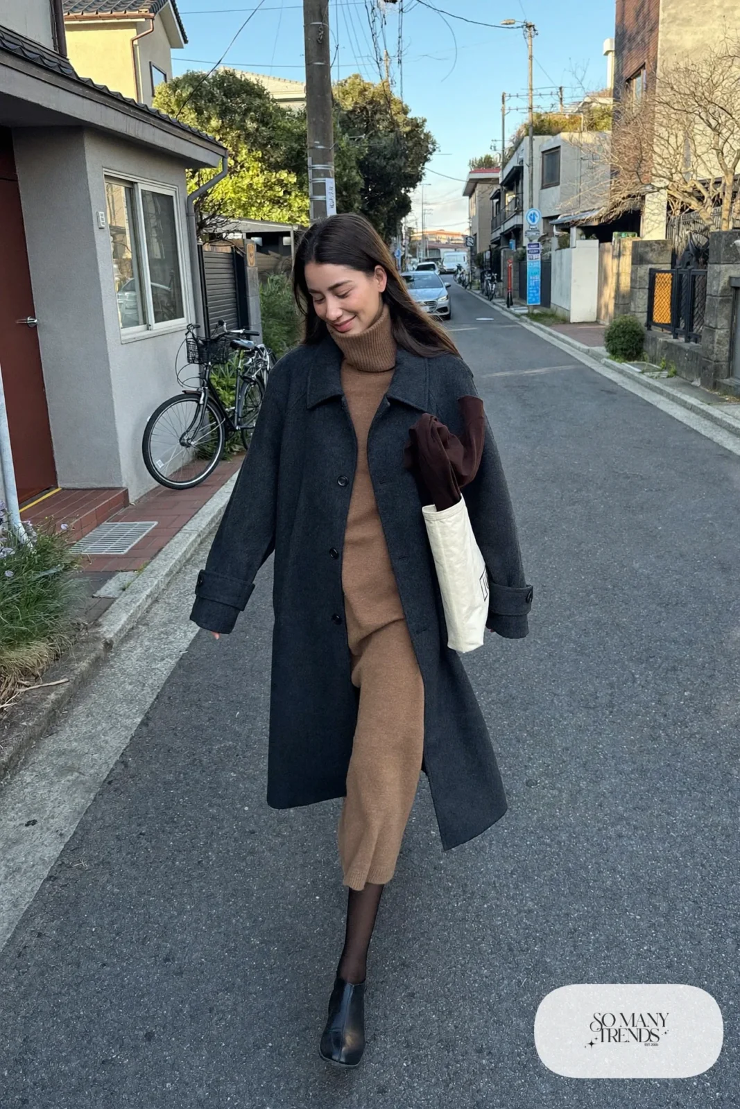 Woman in a camel turtleneck sweater dress, oversized charcoal coat and black flat ankle boots in a Tokyo neighborhood, outfit 18