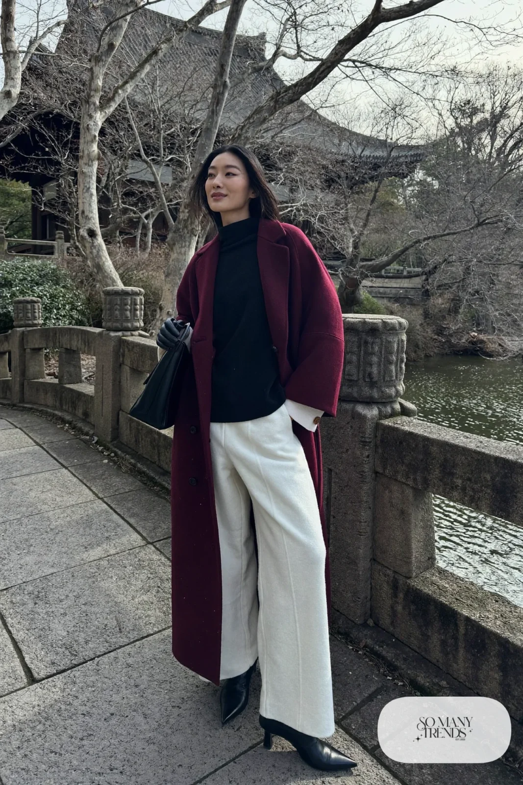 Woman in a long burgundy wool coat, cream wide-leg pants, black knit top and black pointed ankle boots at a Kyoto temple, outfit 20
