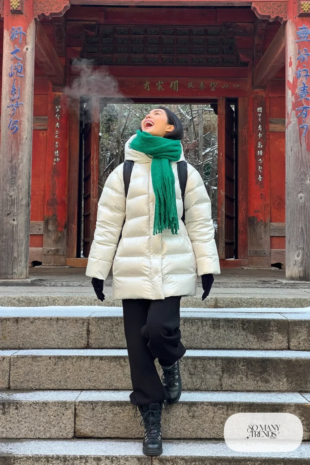 Woman in a pearl white hip-length puffer jacket, black lined pants and black waterproof boots at a snowy temple in Kyoto, outfit 30