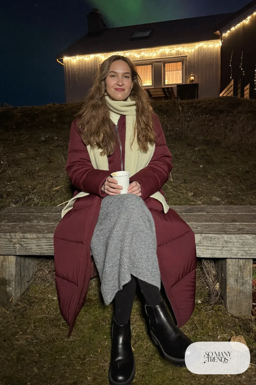Woman in a long burgundy puffer coat, gray knit midi skirt, black tights and black lug-sole boots, outfit 4