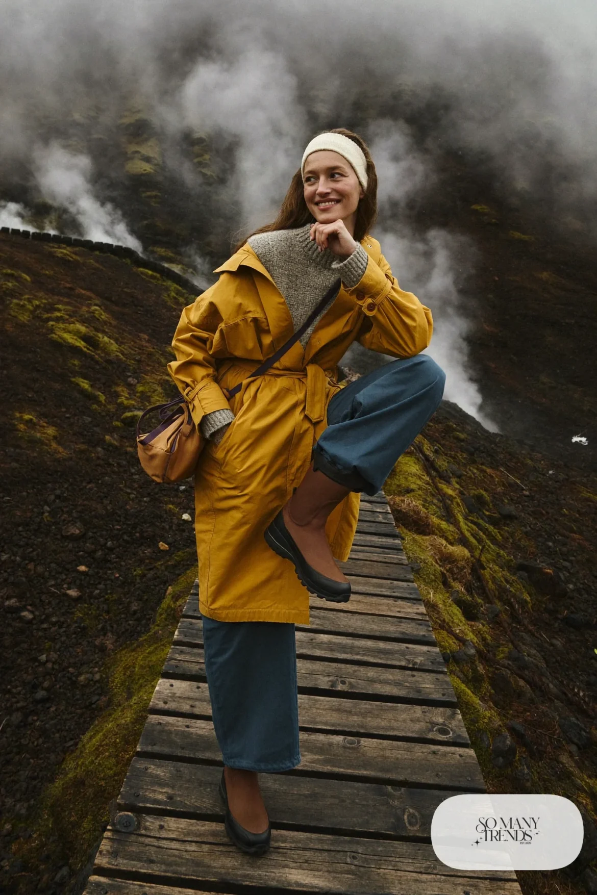 Woman in a mustard water-resistant wrap coat, denim blue pants and brown waterproof boots on a hot spring trail, outfit 15