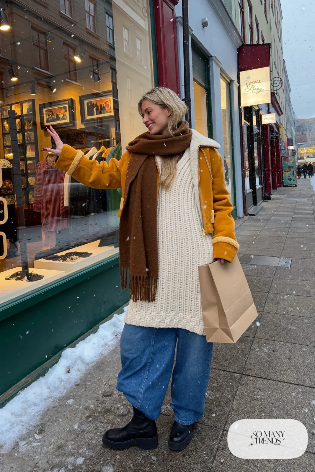 Woman in a mustard cropped shearling jacket, long gray knit, wide jeans and lug boots on Laugavegur street, outfit 21