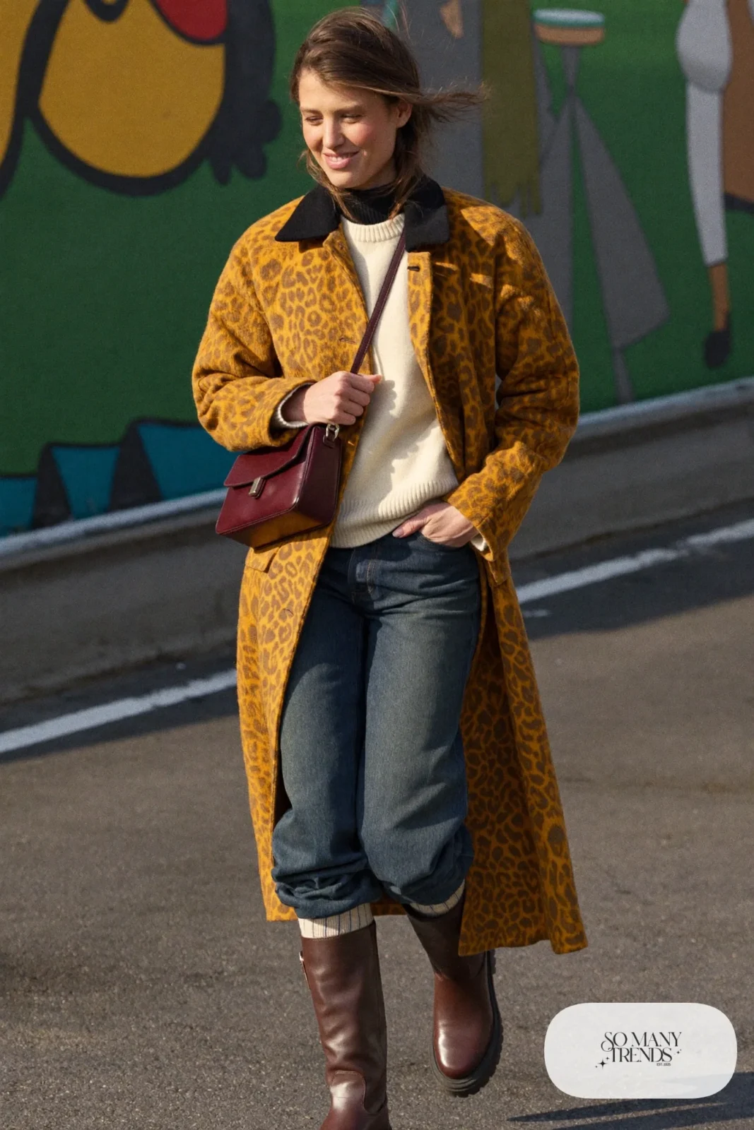 Woman in a long cheetah-print coat, cream sweater, dark jeans and brown boots on a Reykjavik street, outfit 25