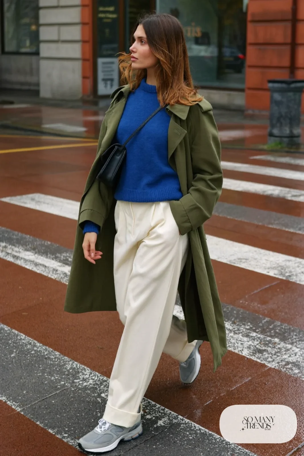 Woman in olive trench coat, cobalt blue sweater, cream wide-leg pants and gray New Balance 9060 sneakers, outfit 3