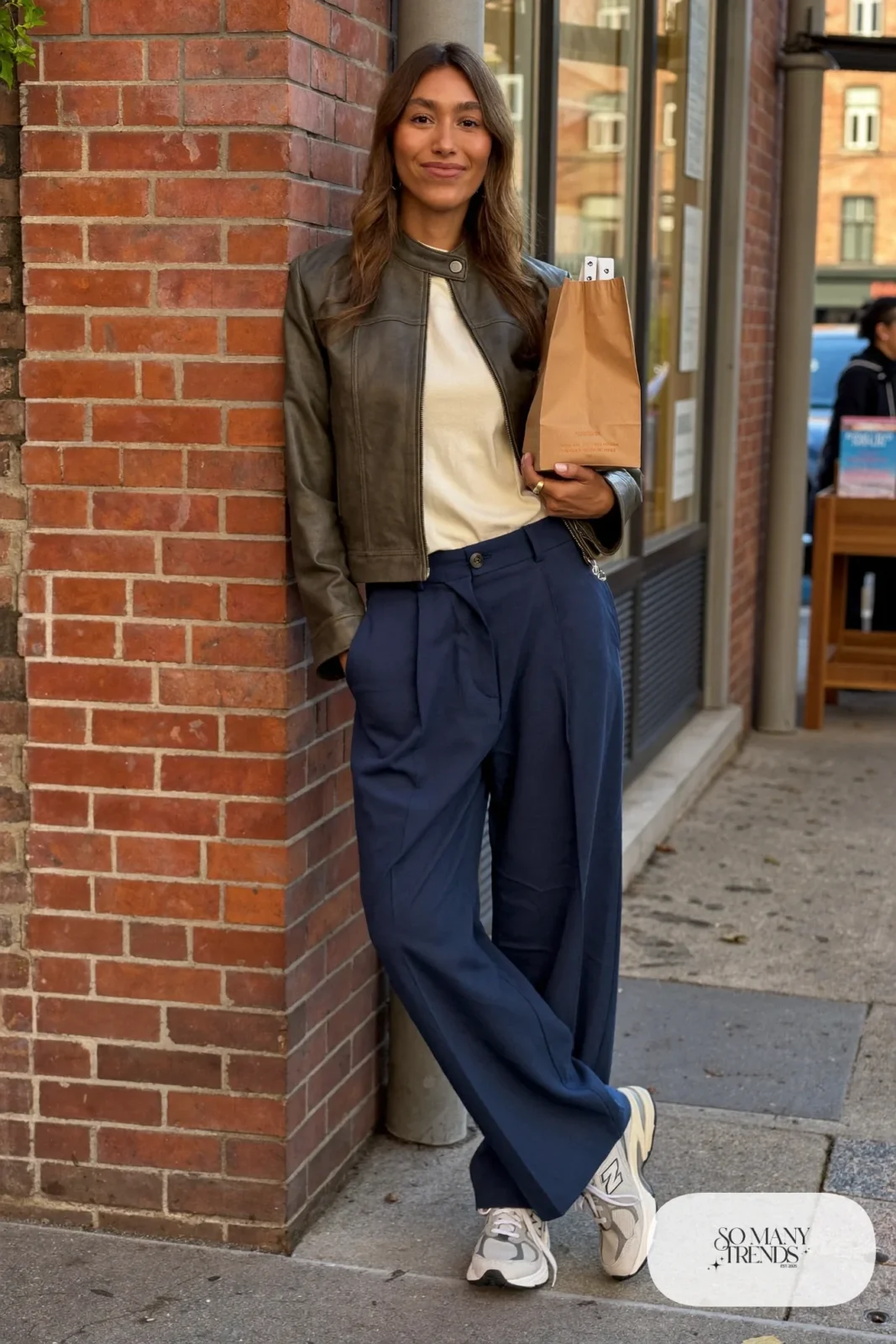 Woman in cropped olive leather jacket, cream tee, indigo wide-leg pants and gray New Balance 9060 sneakers, outfit 7