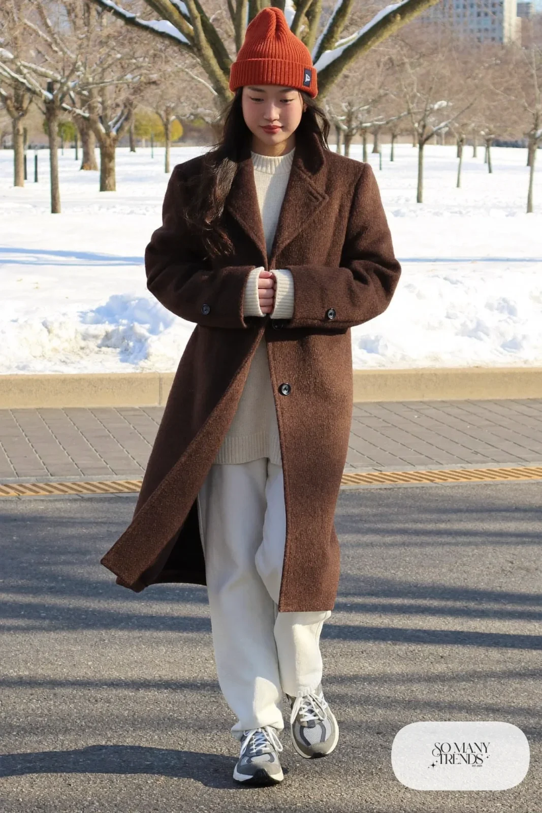 Woman in chocolate brown coat, cream knit, white straight jeans and gray New Balance 9060 sneakers, outfit 19