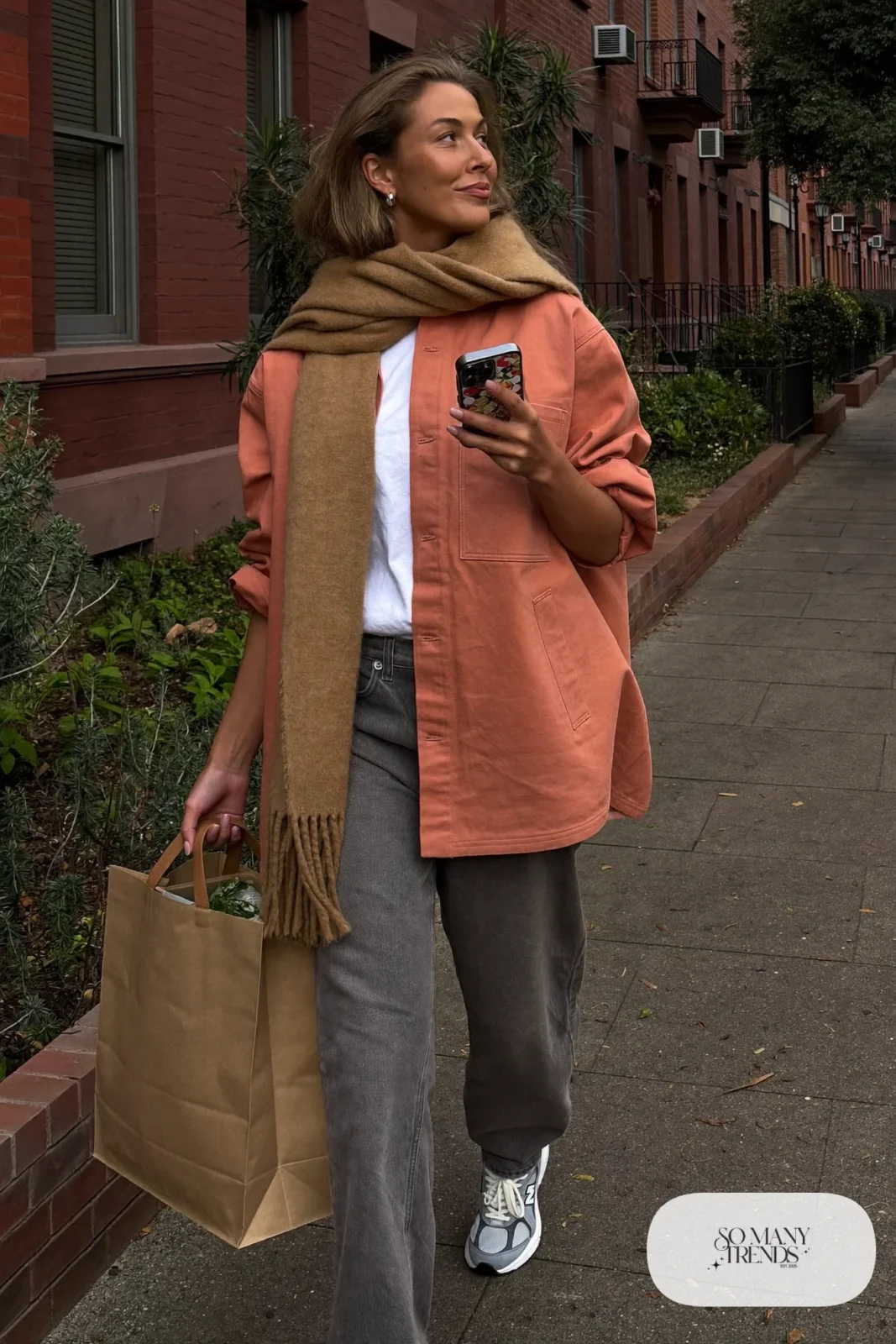 Woman in terracotta overshirt, white tee, gray jeans, camel scarf and gray New Balance 9060 sneakers, outfit 22