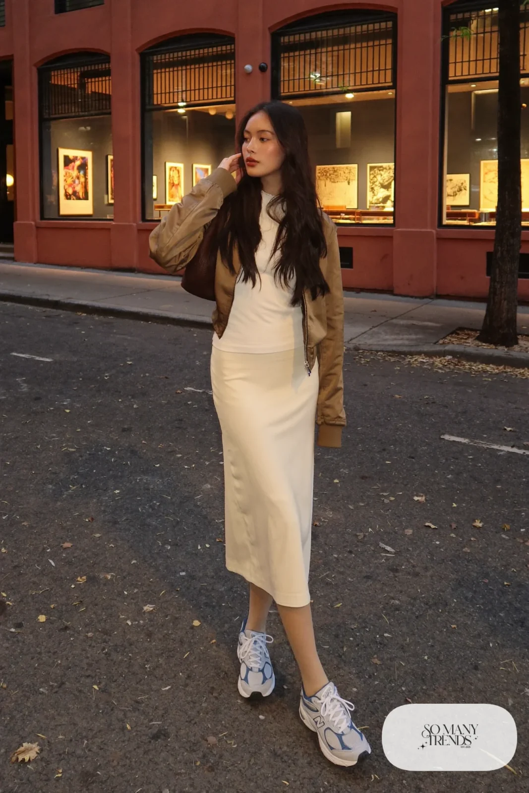 Woman in olive satin bomber, long cream skirt, tights and gray New Balance 9060 sneakers, outfit 28