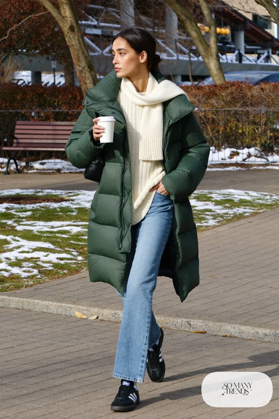 Long forest green puffer coat, cream knit sweater, light straight-leg jeans and black Adidas Samba sneakers, outfit 3