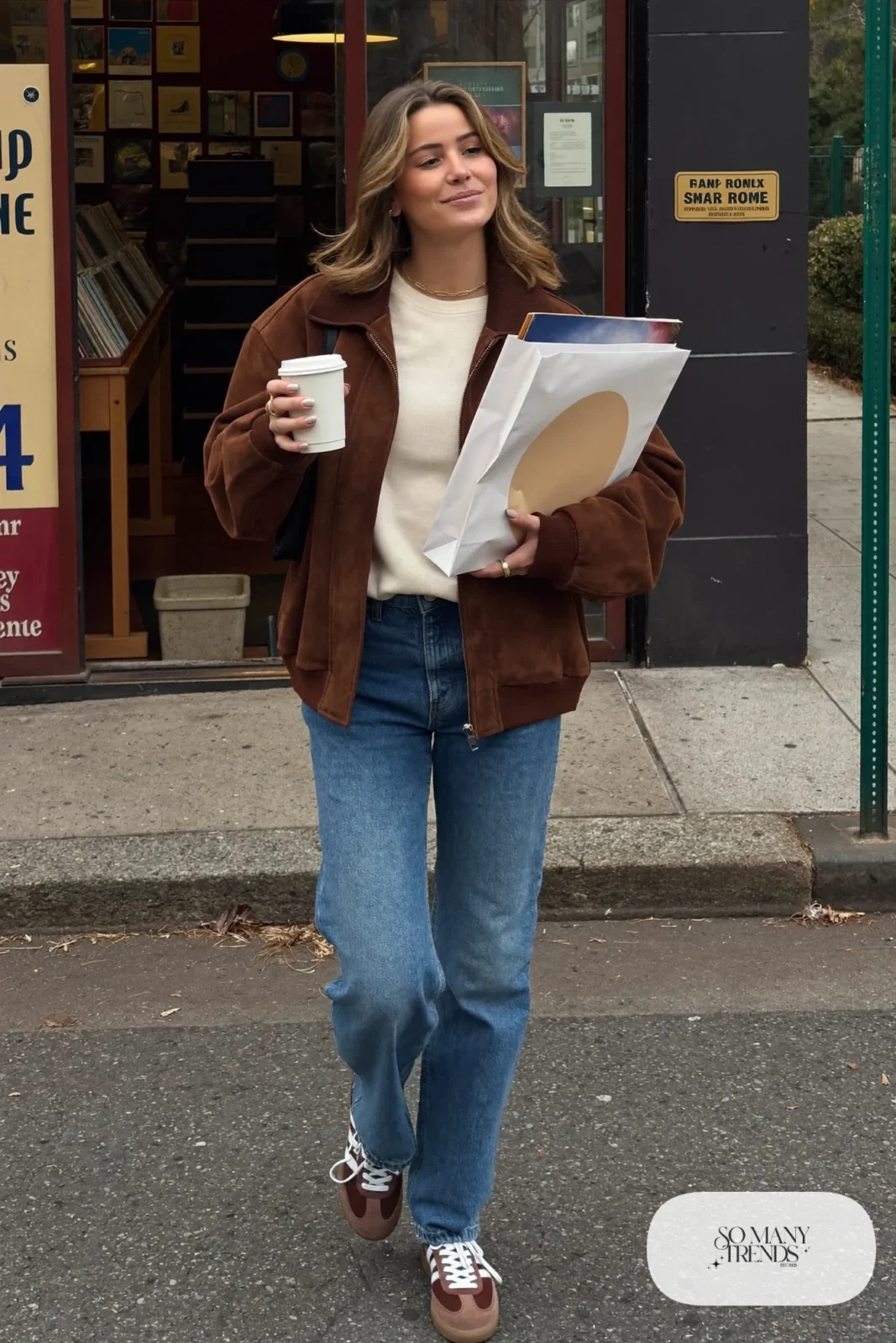 Chocolate brown suede jacket, cream sweater, straight blue jeans and brown-and-white Adidas Samba sneakers with gum sole, outfit 9