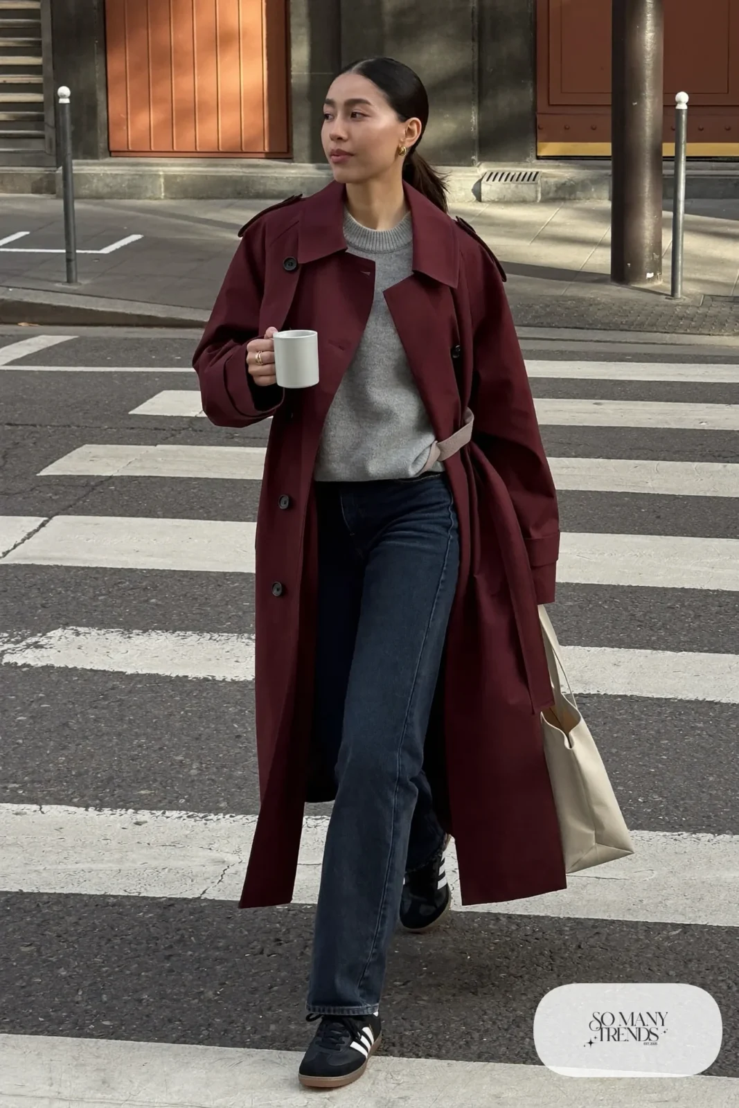 Long burgundy trench coat, gray knit sweater, dark straight jeans and black Adidas Samba sneakers, outfit 10