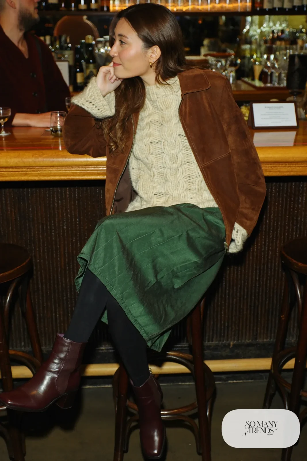 Woman in brown suede jacket, cream knit, bottle green satin skirt and brown boots, outfit 7