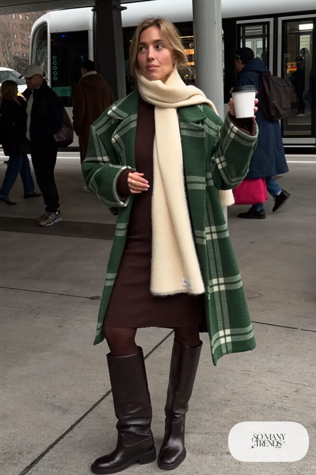 Woman in green plaid coat, brown knit midi dress, cream scarf and tall brown boots, outfit 10