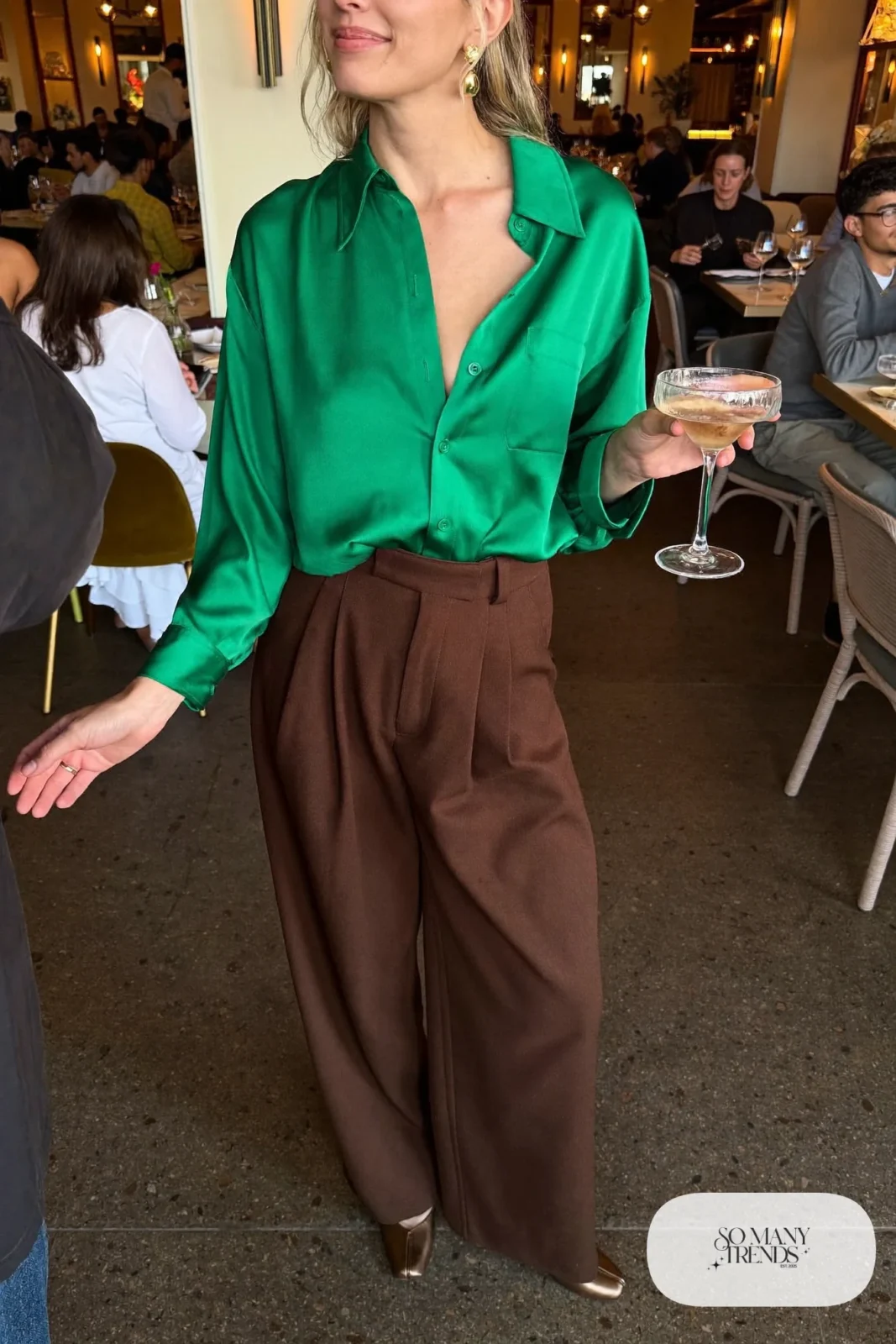 Woman in emerald satin blouse, chocolate pleated wool pants and bronze closed-toe heels, outfit 12