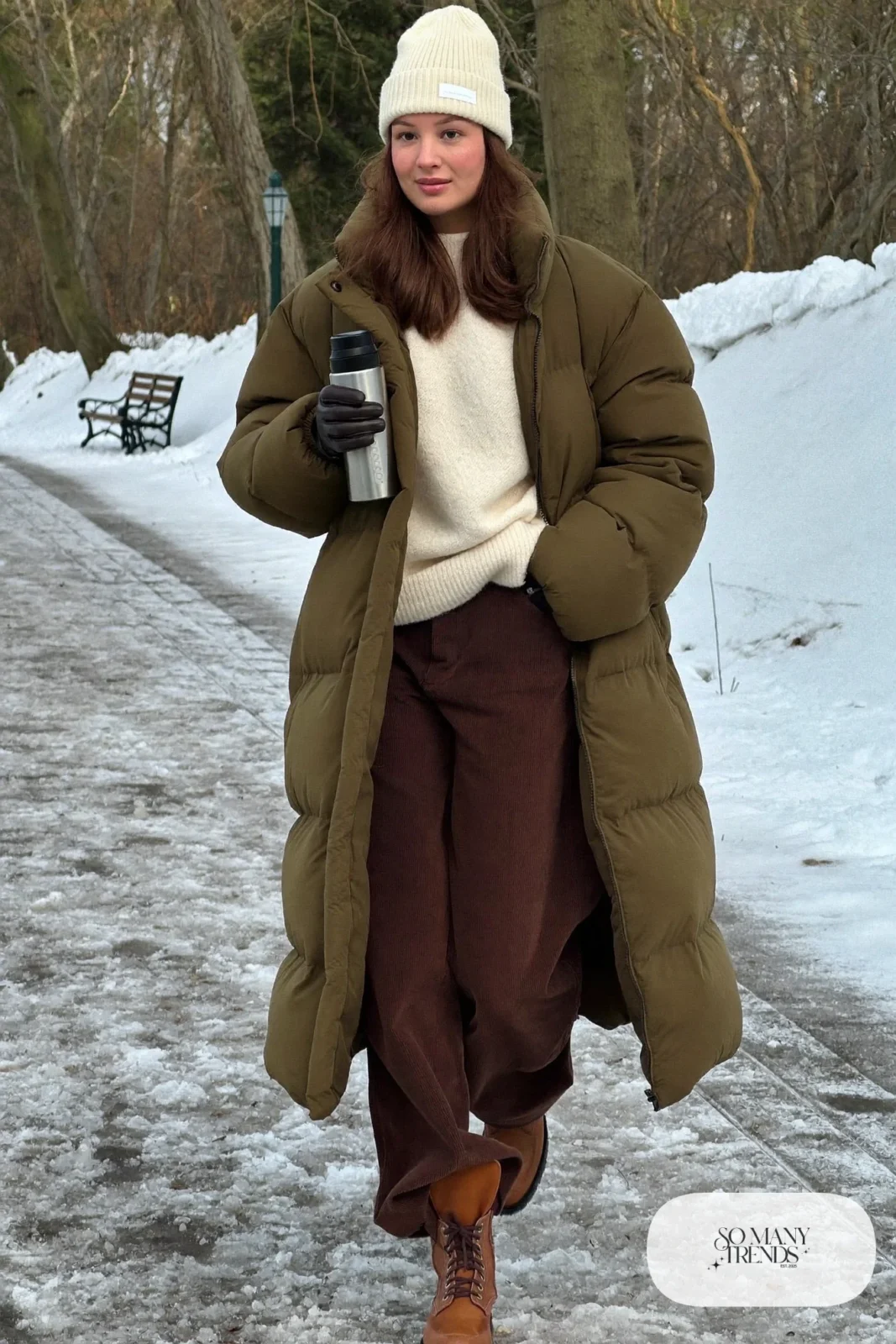 Woman in olive puffer coat, brown corduroy pants, cream beanie and brown boots, outfit 13