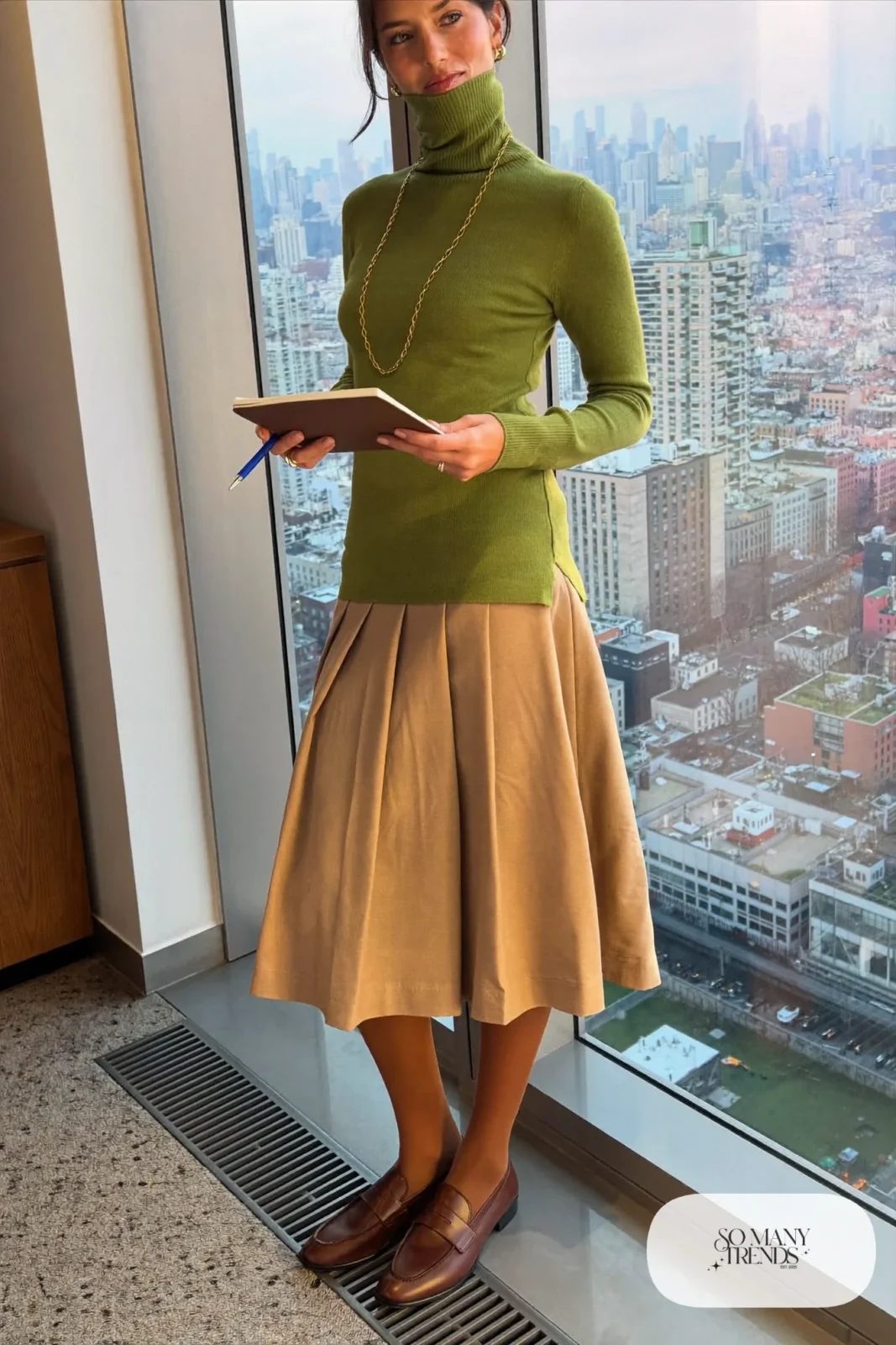 Woman in moss green turtleneck, tan pleated midi skirt, tights and brown loafers, outfit 21