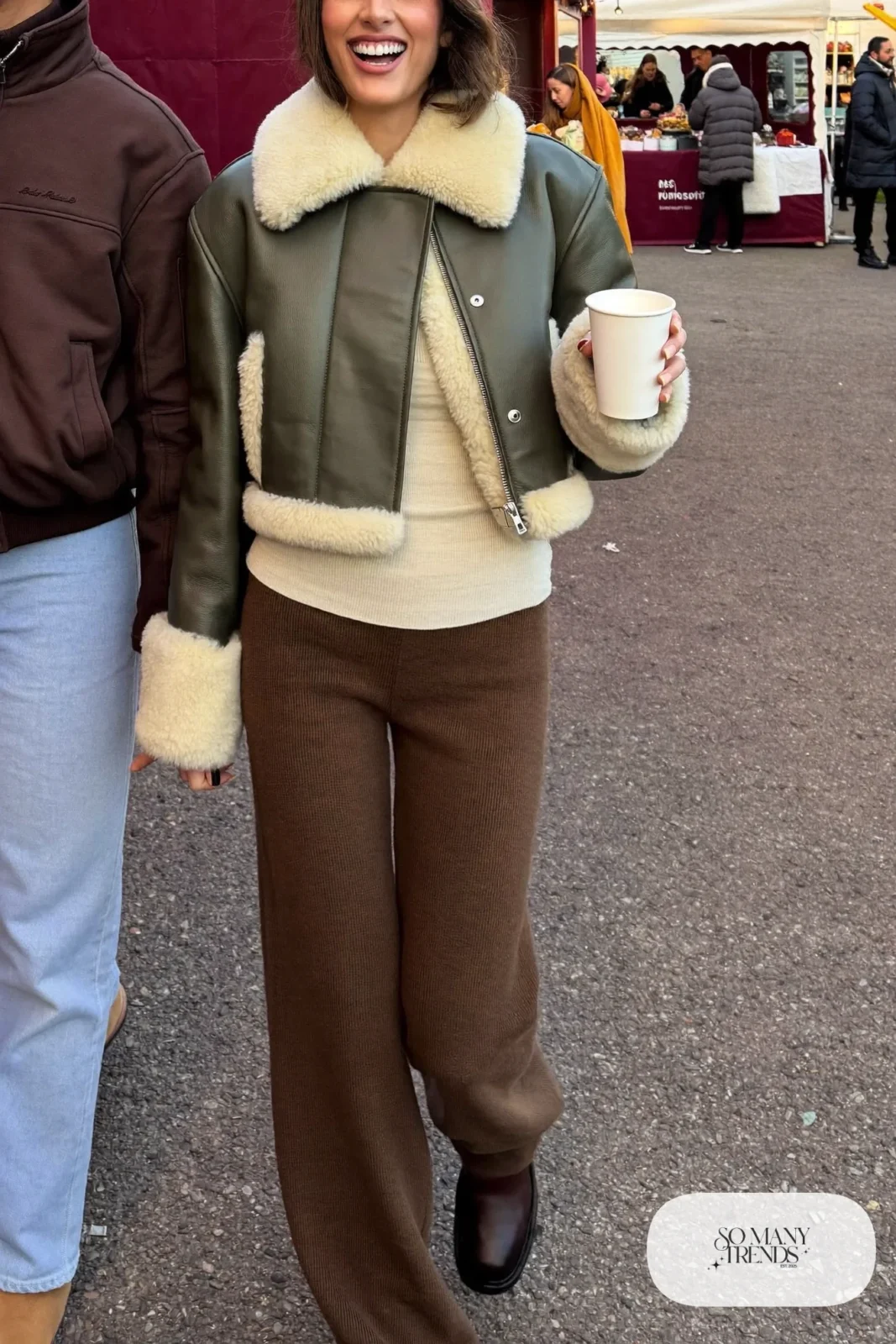 Woman in green shearling-trim jacket, cream tee, brown knit wide-leg pants and boots, outfit 29