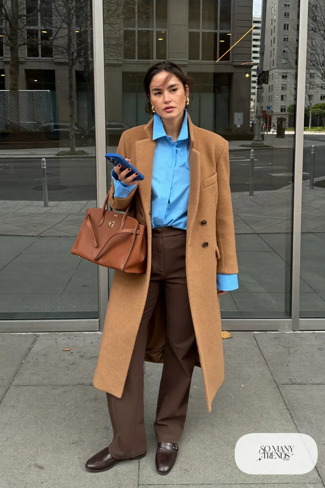 Baby blue poplin shirt under a long camel wool coat with espresso brown straight-leg pants and brown loafers, outfit 2