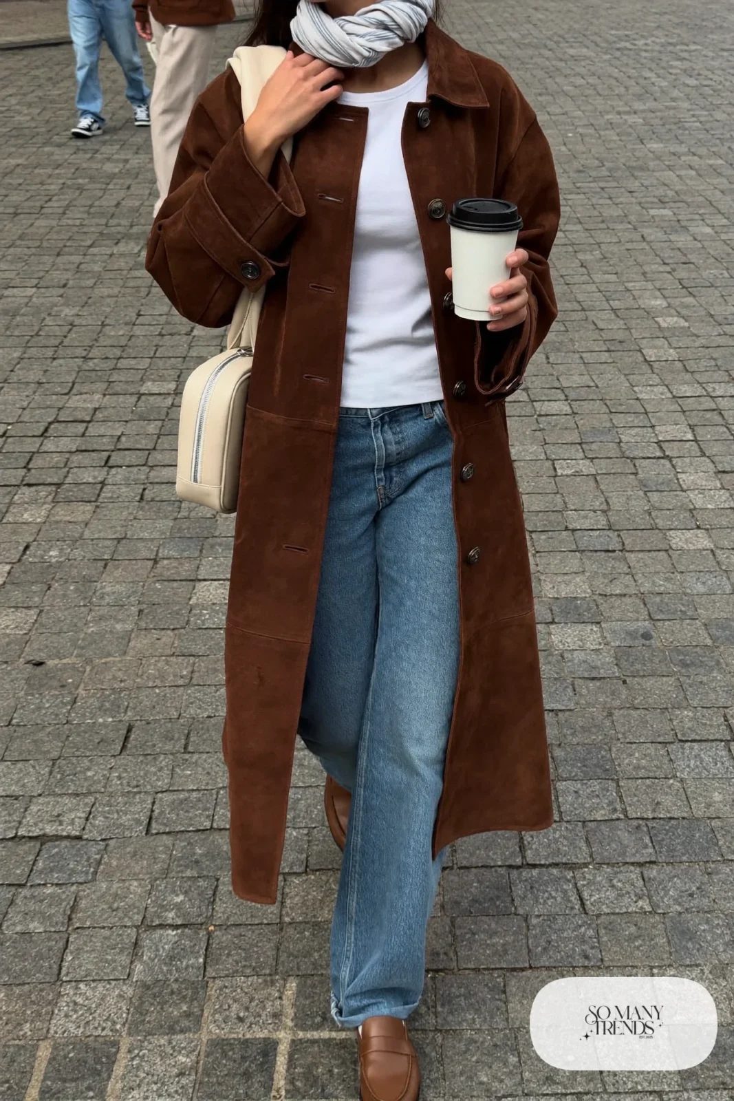 Brown faux suede trench coat belted over a white tee and baby blue straight jeans with tan loafers, outfit 7