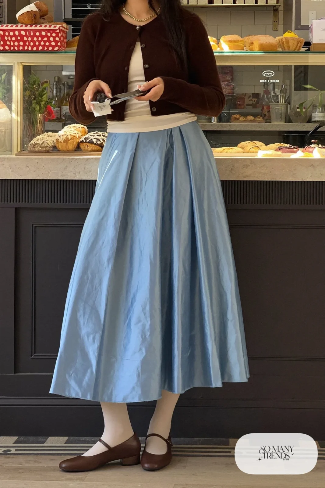 Cropped chocolate brown knit cardigan over a cream tank with a powder blue pleated midi skirt and brown mary jane flats, outfit 8