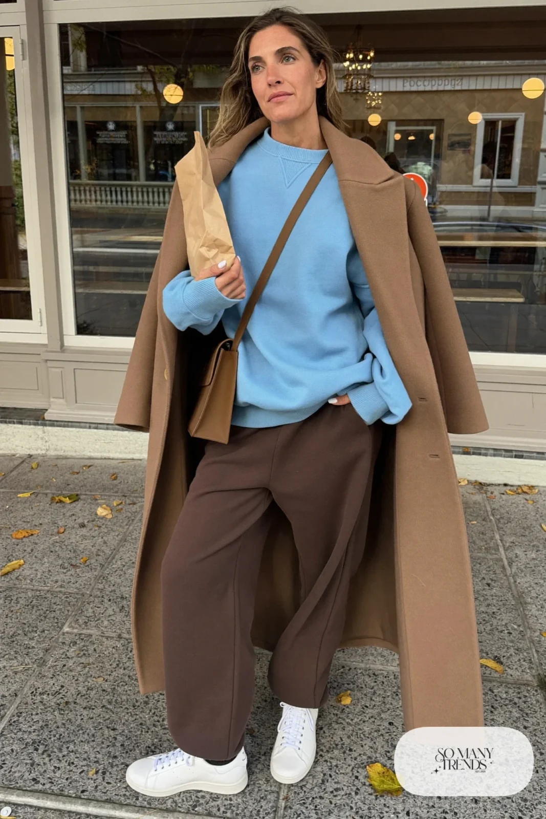 Light blue sweatshirt under a long camel overcoat with chocolate wide-leg knit pants and white leather sneakers, outfit 9