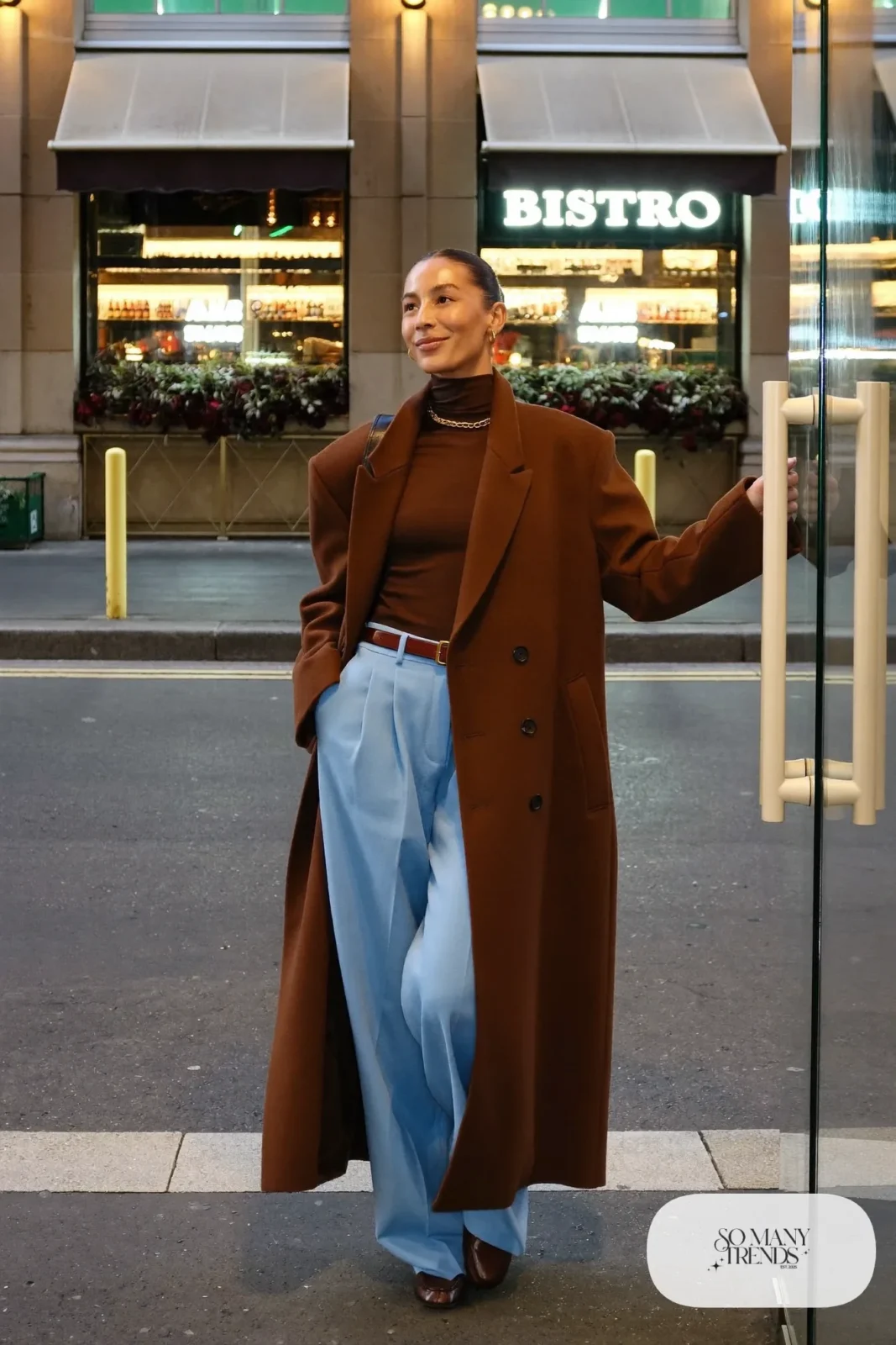 Espresso fine-knit turtleneck tucked into baby blue pleated trousers with a long chocolate coat and brown loafers, outfit 18
