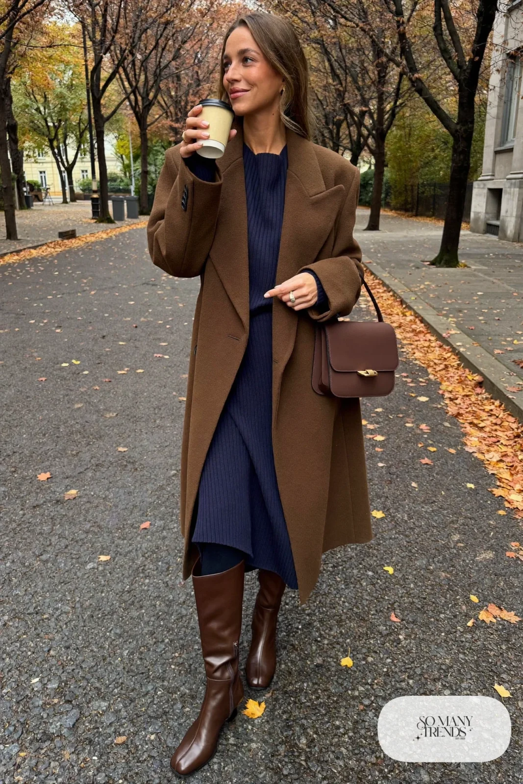 Woman in a camel long coat, navy knit midi dress, navy tights and brown tall boots, outfit 2