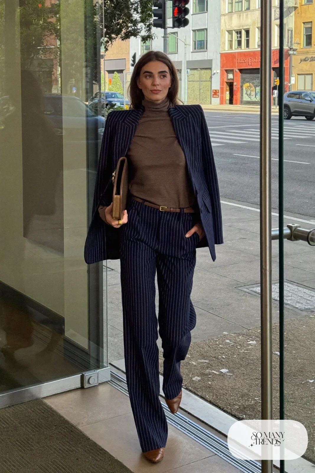 Woman in a navy pinstripe suit, tobacco brown turtleneck, brown leather belt and brown pointed flats, outfit 5