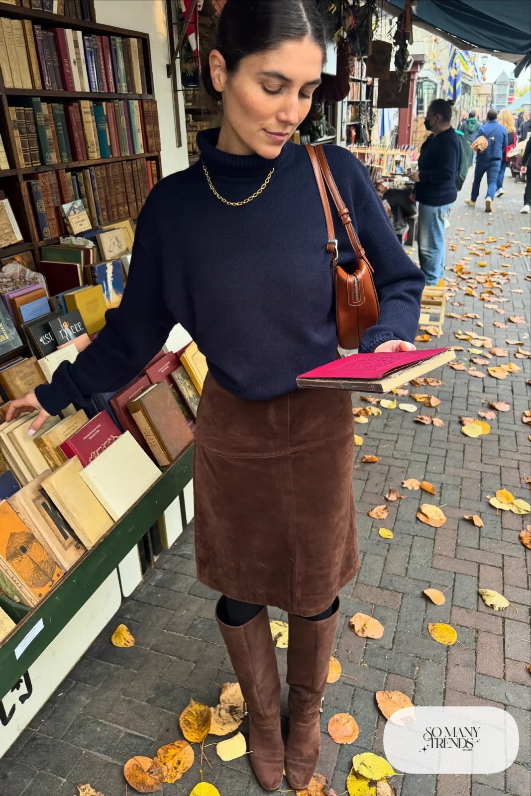 Woman in a navy turtleneck, brown suede midi skirt and brown suede tall boots, outfit 17
