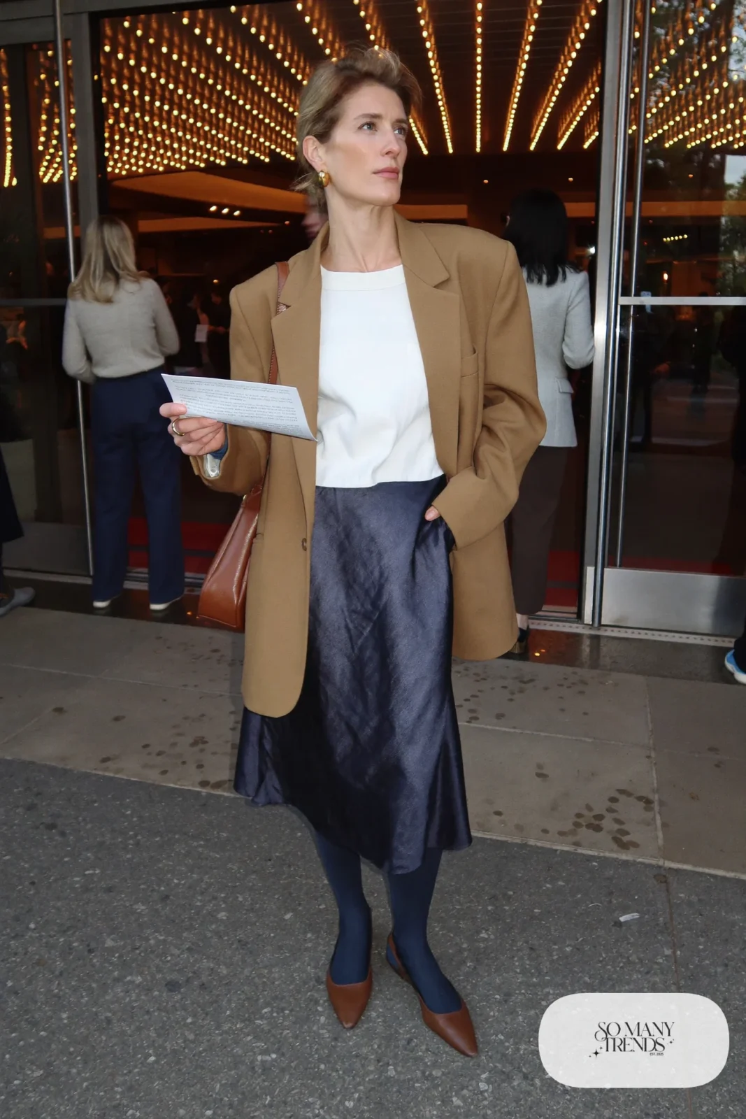 Woman in a camel blazer, white tee, navy satin midi skirt and brown pointed flats, outfit 20