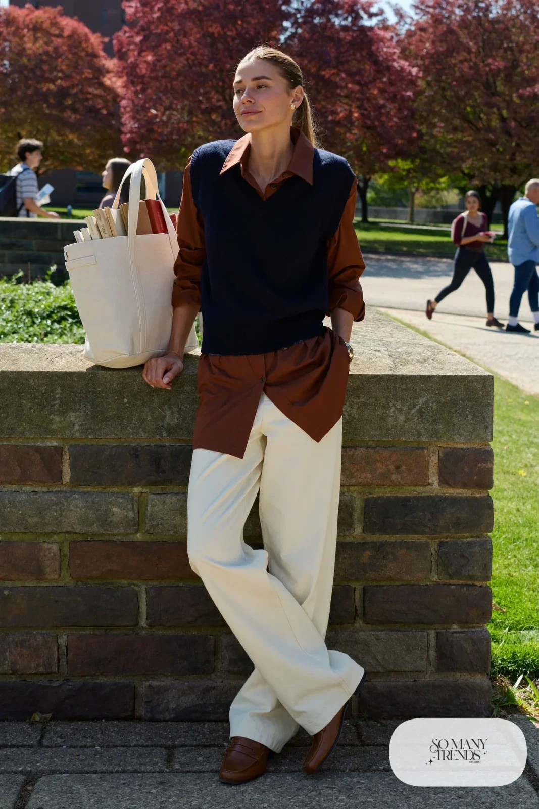 Woman in a navy knit vest, cognac shirt, cream wide-leg pants and brown loafers, outfit 23