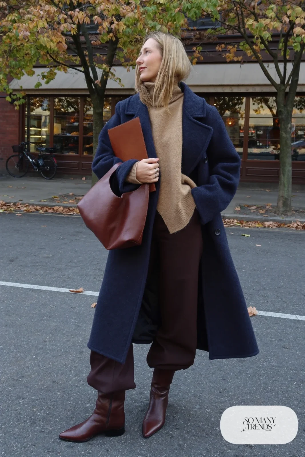 Woman in a long navy coat, camel sweater, chocolate wide-leg pants and tobacco boots, outfit 27