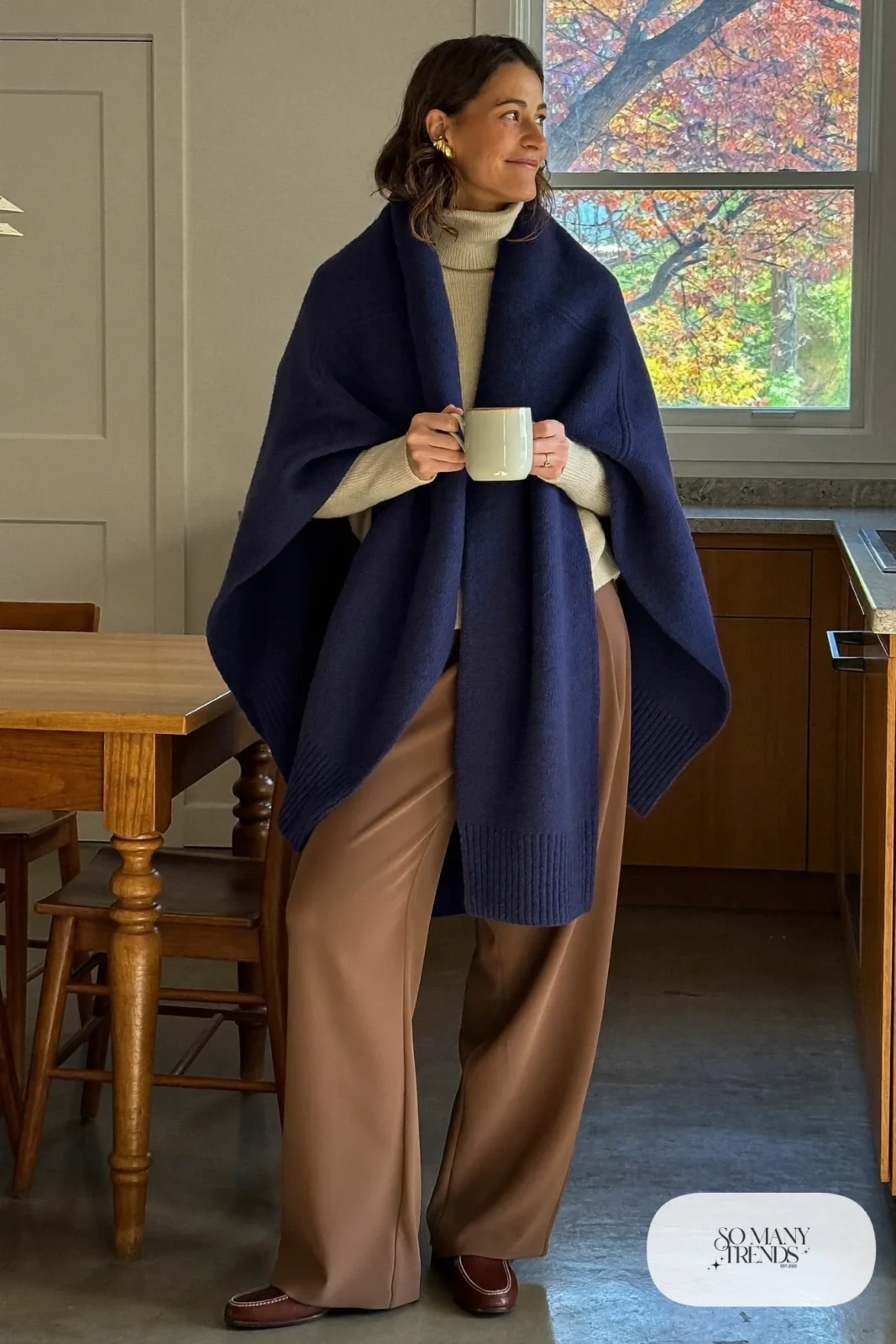 Woman in a navy knit wrap, cream turtleneck, camel wide-leg pants and brown loafers, outfit 29