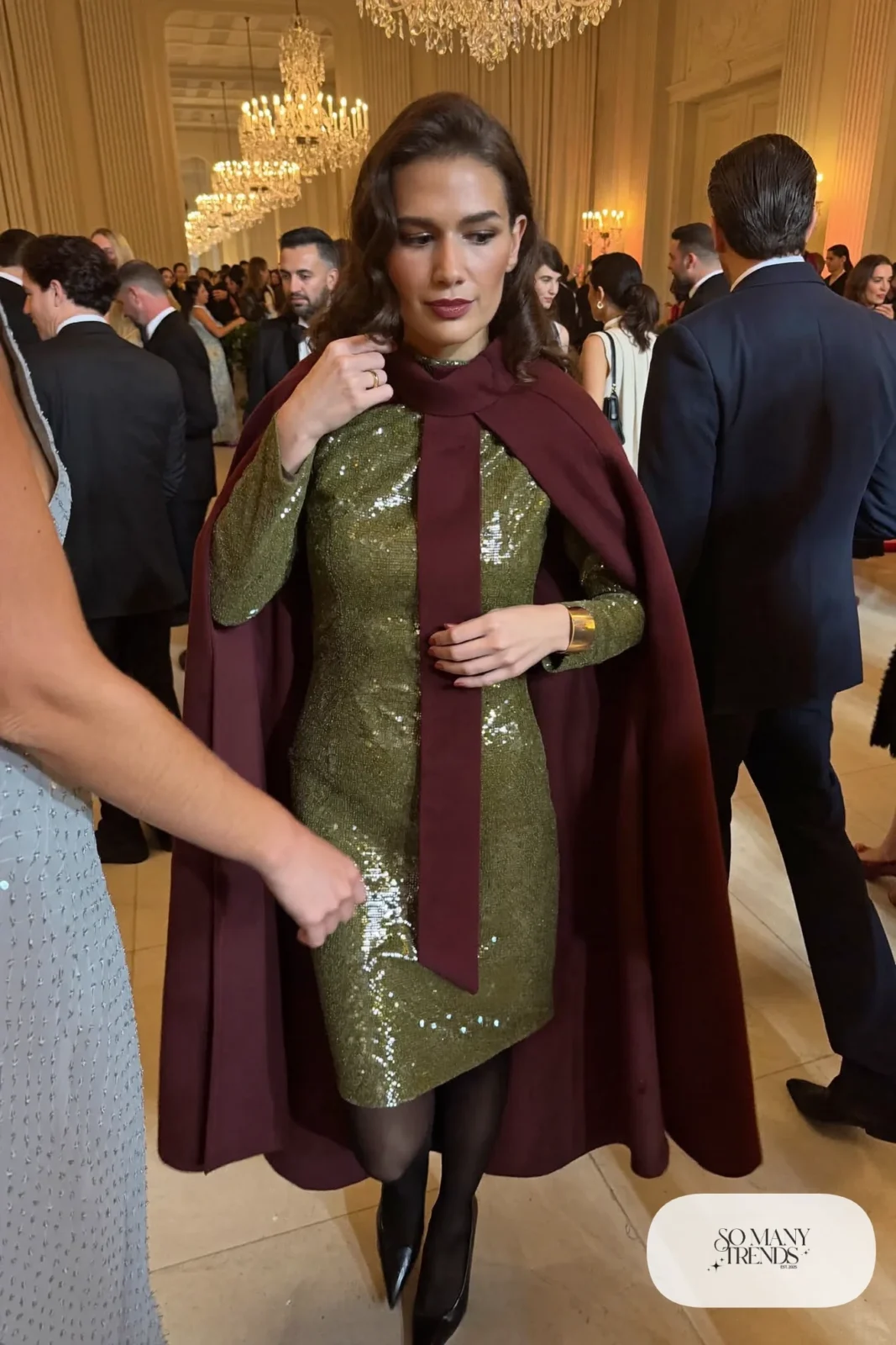 Woman in olive green sequin long-sleeve dress, burgundy wool cape, black tights and black pointed pumps, outfit 5