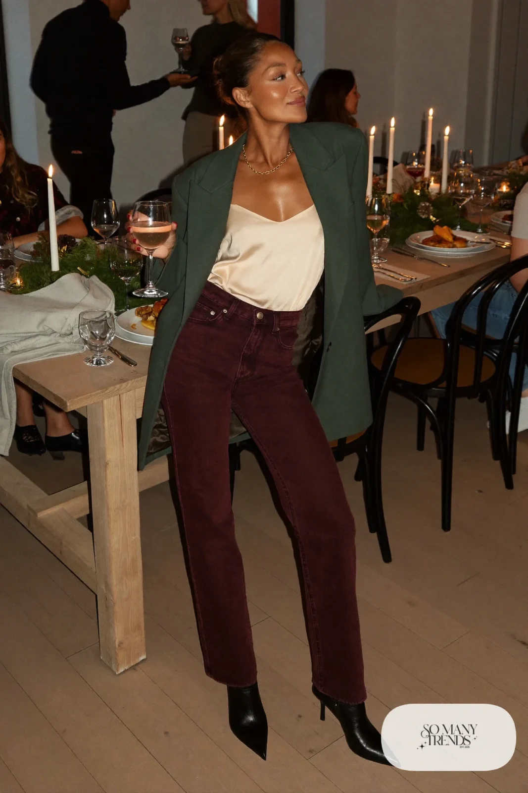 Woman in dark burgundy straight jeans, forest green blazer, cream silk camisole and black pointed ankle boots, outfit 17
