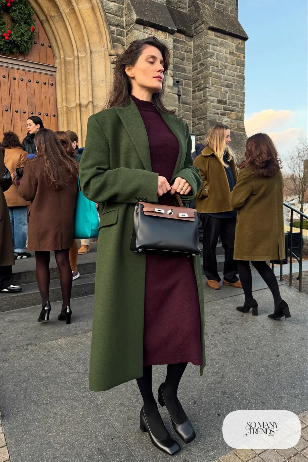 Woman in burgundy knit midi dress, long forest green wool coat, sheer tights and low block-heel pumps, outfit 19