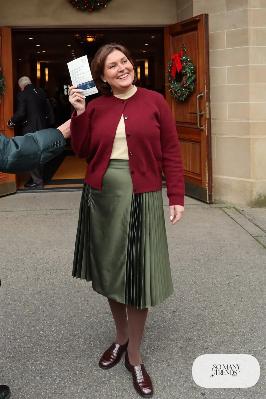 Woman in olive pleated midi skirt, burgundy fine knit cardigan, cream tee, tights and brown loafers, outfit 20