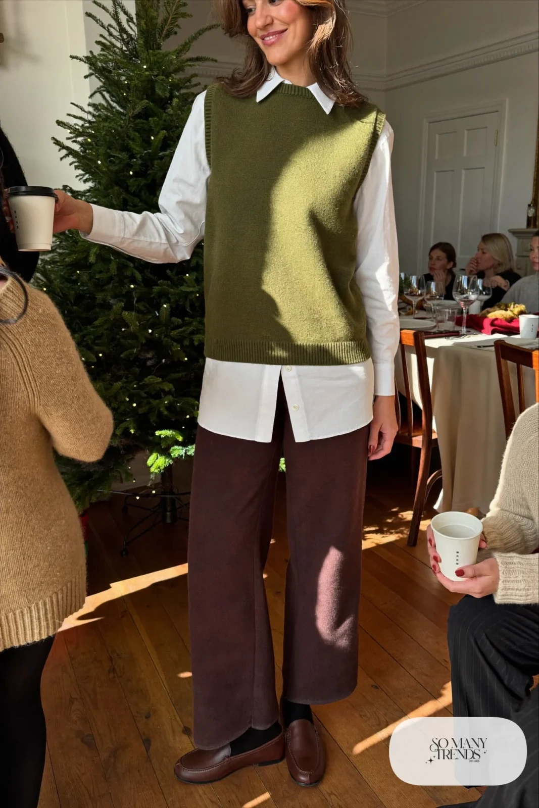 Woman in burgundy wide-leg wool pants, olive green knit vest over white shirt and brown loafers, outfit 22