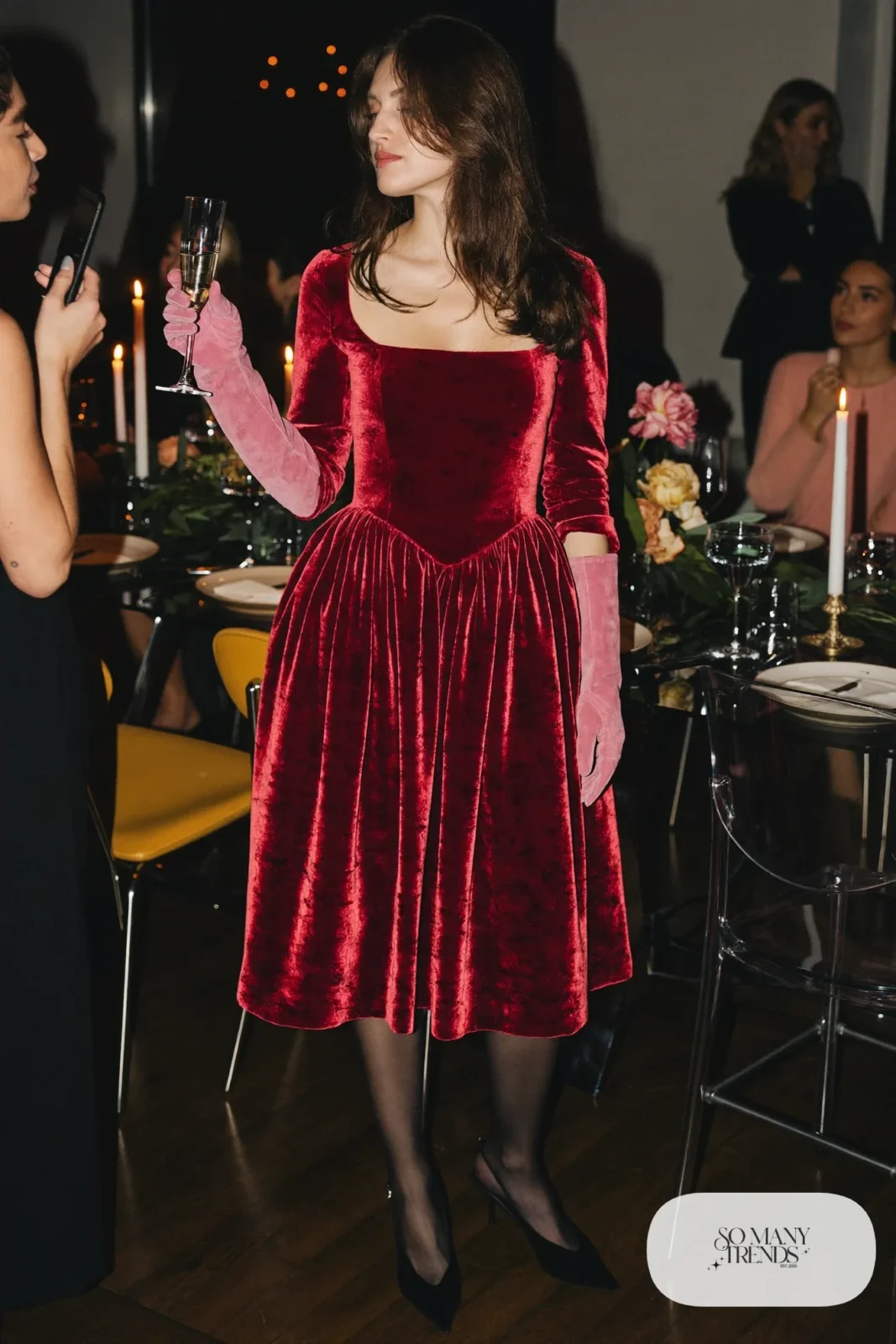 Woman in wine velvet midi dress, long dusty-pink suede gloves, sheer black tights and black slingback pumps, outfit 4